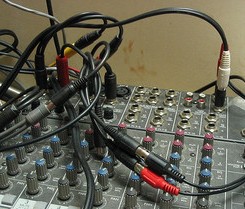 A bunch of tangled cables patching ports on a sound desk