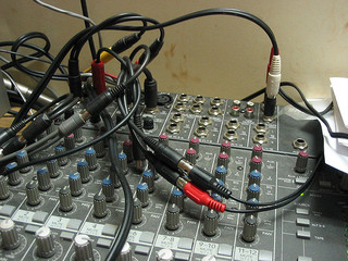 A bunch of tangled cables patching ports on a sound desk