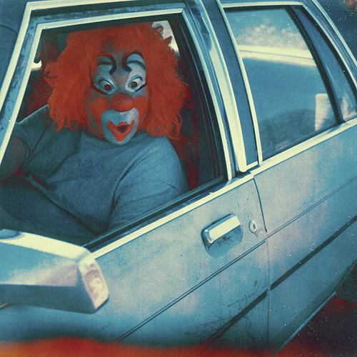 A clown in a car with a surprised expression