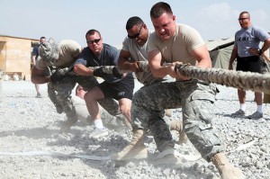 Army soldiers pulling hard on a rope in a tug of war. Teams working together in a DevOps environment concentrate on all pulling together in the same direction.