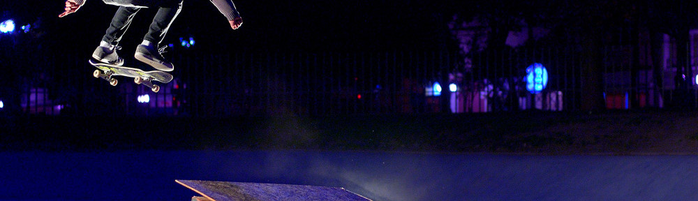 A skateboarder jumping off a wooden ramp at night