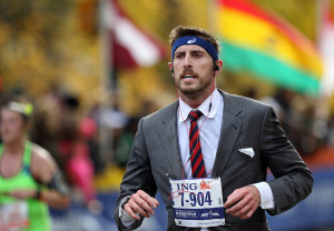 A man in a suit, who probably works for an enterprise, running in a marathon and looking very agile