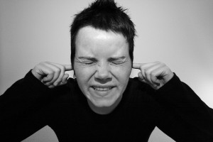 Young woman with fingers in ears and eyes closed