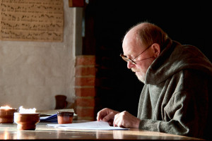 A man reading a thin paper in a cafe, possibly a Hiring Manager reading a resume.