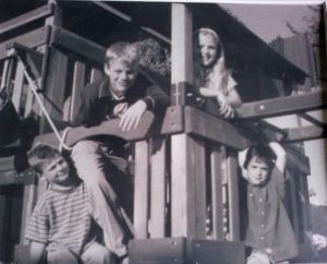 Black and white photo of four kids on an outdoor cubby house