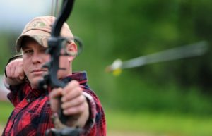 An archer shooting an arrow past the viewer towards a target